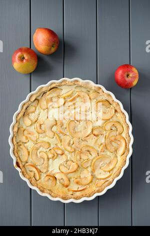 Apple tart with whole apples on grey stripped background overhead view Stock Photo