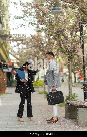 Two casual dressed business people are talking under the falling flower leafs Stock Photo