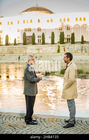 Two amazing senior businessmen are talking by the river Stock Photo