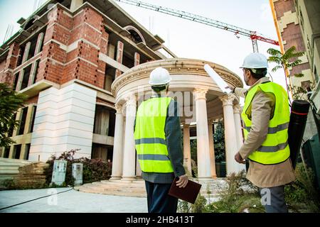 Two construction workers are looking at the construction area while talking Stock Photo