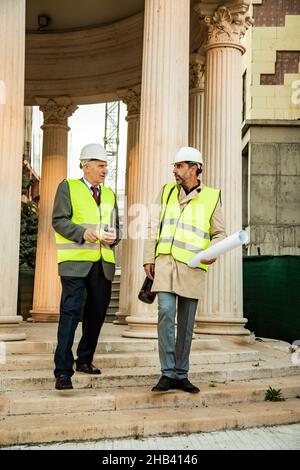 Two construction workers are walking and talking to each other about the plans Stock Photo