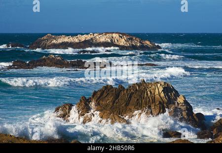 Inspiring  beauty of pacific ocean rolling waves in a rocky coastline, with slight hazy blue sky of Pacific Grove central coast travel destination. Stock Photo