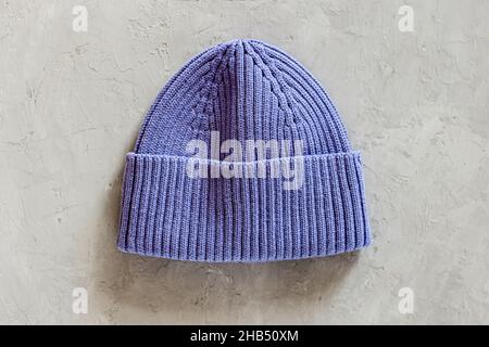 Flat lay of knitted hat on gray concrete background. Color of the year 2022 very peri. Trendy color concept, mockup with copy space Stock Photo