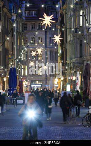 Leipzig, Germany. 15th Dec, 2021. Fairy lights adorn Nikolaistrasse in Leipzig's city centre. At Christmas time, the Transport and Public Works Department installs around 5,300 lamps in the streets and alleys of the city centre in addition to the public lighting. More than half of these are now energy-efficient LED lamps. Garlands of lights, Herrnhut stars and other Christmas motifs create a festive atmosphere. Along the Promenadenring there are around 174 fairy lights. Credit: Jan Woitas/dpa-Zentralbild/ZB/dpa/Alamy Live News Stock Photo