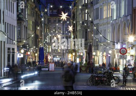 Leipzig, Germany. 15th Dec, 2021. Fairy lights adorn Nikolaistrasse in Leipzig's city centre. At Christmas time, the Transport and Public Works Department installs around 5,300 lamps in the streets and alleys of the city centre in addition to the public lighting. More than half of these are now energy-efficient LED lamps. Garlands of lights, Herrnhut stars and other Christmas motifs create a festive atmosphere. Along the Promenadenring there are around 174 fairy lights. Credit: Jan Woitas/dpa-Zentralbild/ZB/dpa/Alamy Live News Stock Photo