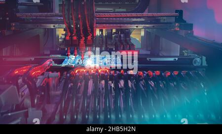 Production of modern productive electronic chips and boards on automatic SMT machine - Digital technologies for automation of industry. Red neon lights illuminate Chip Components for automation test. Stock Photo