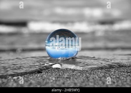 glass globe on the beach of the baltic sea. Black and white photo with a color glass ball Stock Photo