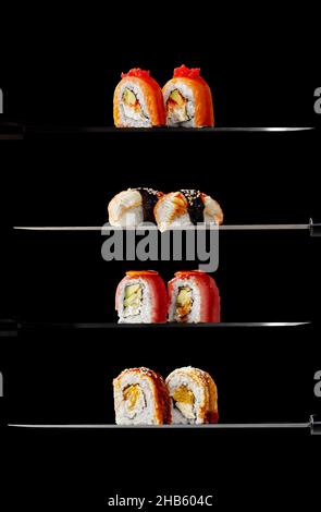 Philadelphia rolls with salmon, unagi rolls, uramaki with tuna and nigiri sushi with eel on knife blades on black background Stock Photo