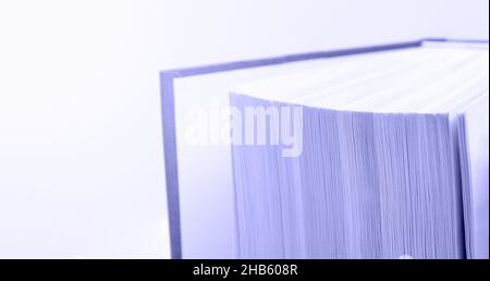 Abstract background toned in trendy Very Peri - Color Of The Year 2022. Fan of book pages with copy space. Macro view of the book in the haze. Concept Stock Photo