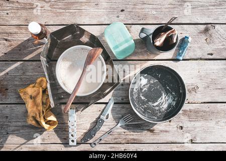 Camp cooking accessories on the wooden table with boiling rise. Food and lunch while on camping vacation. Vintage style. Stock Photo