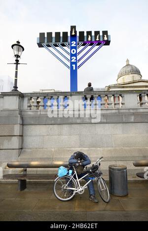 London, England, UK. Menorah in Trafalgar Square, in front of the National Gallery, to celebrate Hanukkah 2021. Man resting with his bike Stock Photo