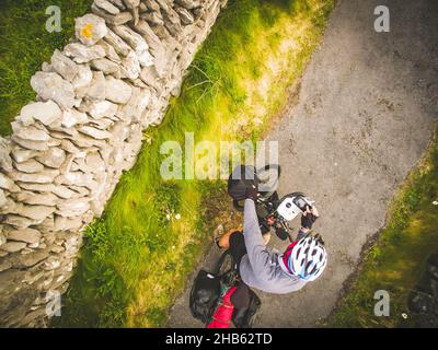 Cyclist is standing with bicycle and controlling drone with remote controller Stock Photo