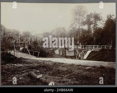 Bridge over the Alue Teungoh River, Bridge on the Gajo road over the Alue Teungoh River. On the bridge soldiers and an overseer on horseback pose, next to the new bridge is still the old bridge (demolished on 25 October 1908). Framed photo in an album of 87 photos about the construction of the Gajo road on North Sumatra between Bireuen and Takinguen between 1903-1914., anonymous, Noord-Sumatra, 1903 - 1913, photographic support, height 138 mm × width 200 mm Stock Photo