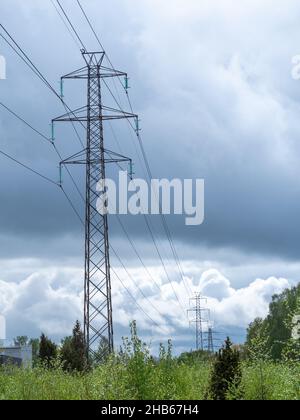 High voltage power lines pylons and electrical cables on a clear blue sky background. Stock Photo
