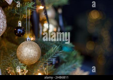 Golden Christmas decoration bauble on tree with lights Stock Photo