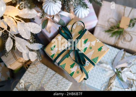 Wrapped in craft paper gift boxes near Christmas tree Stock Photo