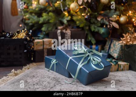 Wrapped in craft paper gift boxes near Christmas tree Stock Photo
