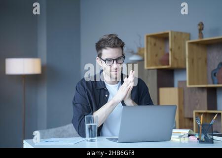 Young handsome austrian male freelancer wearing glasses looking at computer screen attentively Stock Photo