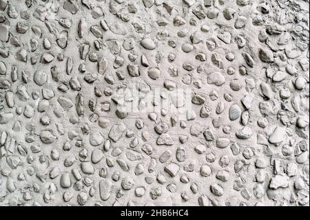 Gray cement wall with little round stones close up. Stock Photo