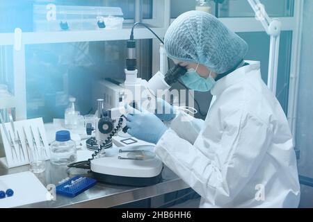 Young scientist looking through a microscope in a laboratory. Medical Research Laboratory. Stock Photo