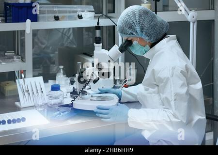 Female scientist looking through a microscope in laboratory. Stock Photo