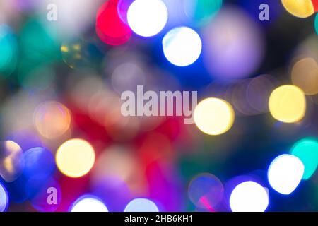 Defocused multicolored holiday lights. Christmas background with a festive Christmas tree with glowing garlands. Stock Photo