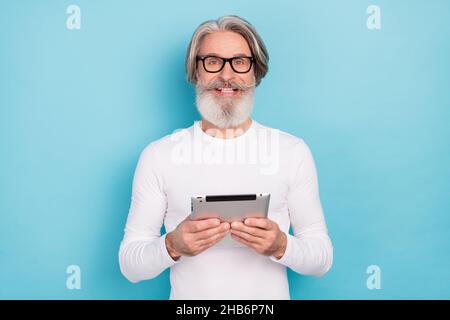 Portrait of attractive cheerful grey-haired man using device blogging analyzing isolated over bright blue color background Stock Photo