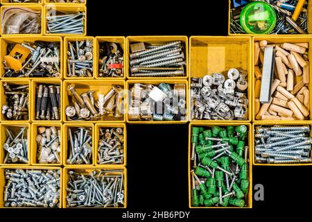 Yellow case with small construction objects. Many storage compartments filled with builders accessories containing screws, nuts, bolts, nails and othe Stock Photo