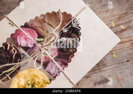 closed box with different cakes wrapped with thread, on a wooden background. Assorted cakes in a craft box Stock Photo