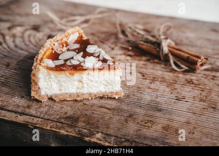 piece of caramel cheesecake with cinnamon sticks on a wooden background, top view. Cheesecake new york, copy space Stock Photo