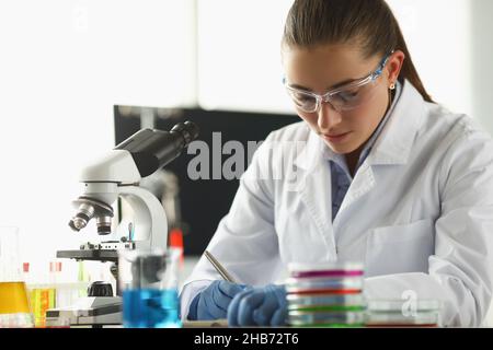 Concentrated chemist worker write down thoughts on investigation project in lab Stock Photo
