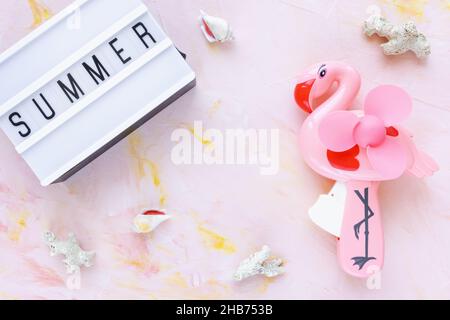 Abstract summer background with text SUMMER seashells and hand flamingo fan on pink. Lifestyle, planning sea vacation, summer holidays concept. Flat lay, top view, copy space Stock Photo