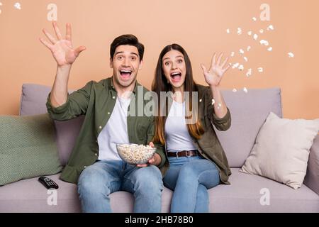 Photo of funky guy lady buddies sit couch watch series throw pop corn air living room isolated over beige color background Stock Photo