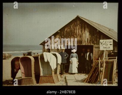 Bicycle shed in Wijk aan Zee, with a number of wicker bath chairs in the foreground, Four men and a woman in the doorway of a bicycle shed on the beach, with a number of wicker bath chairs in the foreground, North Sea beach., Adolphe Burdet (circle of), anonymous (rejected attribution), Netherlands, 1907 - 1930, glass, slide, height 88 mm × width 118 mm Stock Photo