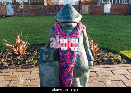 Statue of Andy Capp,a famous cartoon character created by Reg Smythe and featured in the Daily Mirror newspaper for many years. Wearing a RNLI scarf Stock Photo