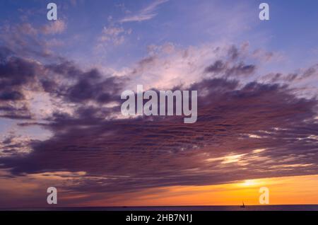Fiery sunset on the sea. The silhouette of a ship is visible on the horizon. Beautiful scenic landscape with dramatic cloudy sky at sunset in Anapa, B Stock Photo