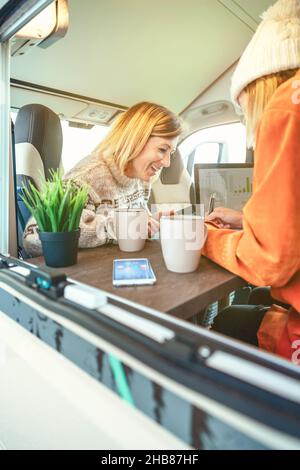 Women laughing while telecommuting in a camper van Stock Photo