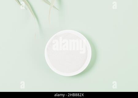 Cosmetic clay powder in bowl on green background, top view close up Stock Photo