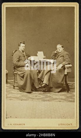 Portrait of two men, one of whom gives the other drink from a bottle in ...