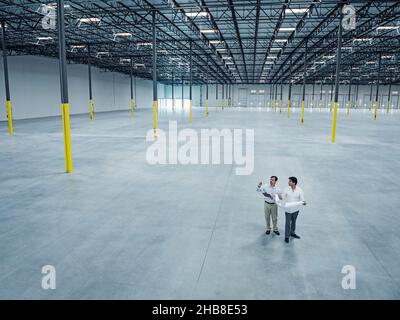 Architects with blueprint talking in empty warehouse Stock Photo