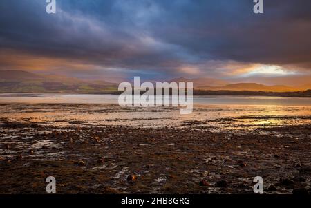 A winter sunset over the Menai Strait looking towards the Snowdonia mountains from Beaumaris, Isle of Anglesey, North Wales Stock Photo