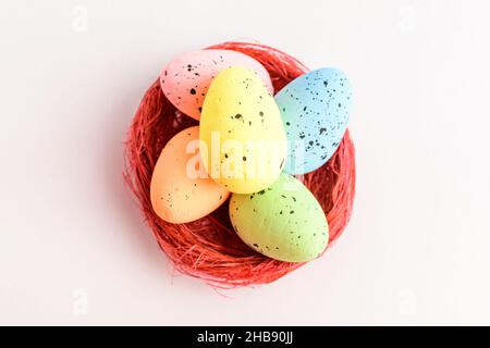 Mixed colored decorative red Easter eggs in a red rustic basket isolated on a white table Stock Photo