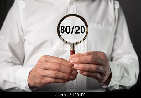 80 20 pareto principle concept, text through magnifying glass in business man hands. Stock Photo