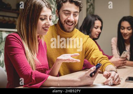 Friends reunion party indoor with group of young people using smartphones at home Stock Photo