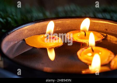 Closeup of candles made from nutshells and beeswax floating in water - old Christmas custom Stock Photo