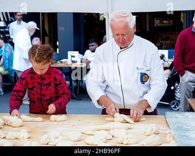 A girl taking a baking lesson from a old baker at a local market in Lucerne, Switzerland Stock Photo
