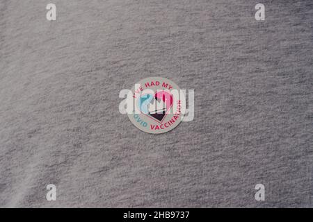 London, UK - December 17, 2021: Close up of NHS Vaccination programme I've Had My Covid Vaccine sticker on a grey t-shirt Stock Photo