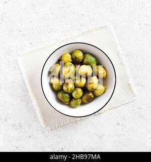 Roasted brussles sprouts in bowl over light stone background. Top view, flat lay Stock Photo
