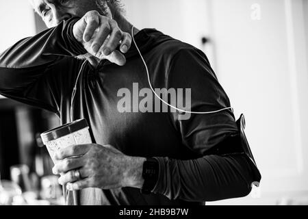 Senior man drinking a smoothie in his kitchen after a run Stock Photo