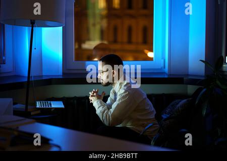 Thoughtful young businessman look at laptop monitor analyze financial report and sales late at night Stock Photo